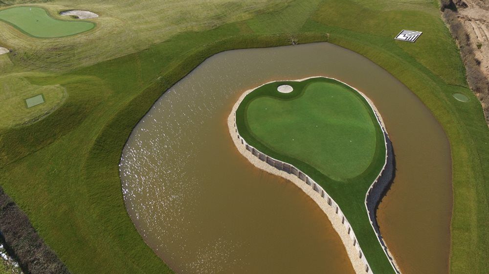 Detroit and all of Michigan Aerial view of a vibrant green synthetic grass island in a natural pond on a golf course